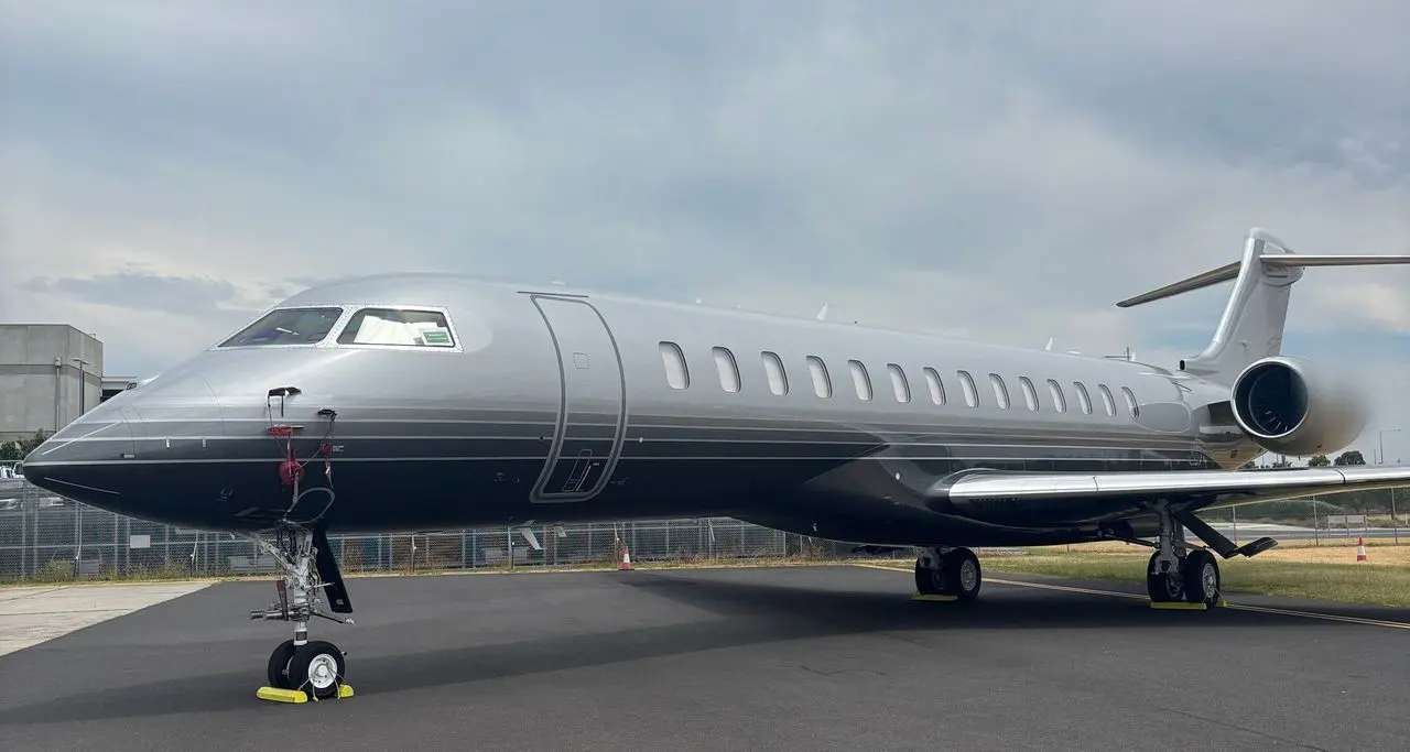 Grey long-range private jet nose-on beneath a soft grey sky