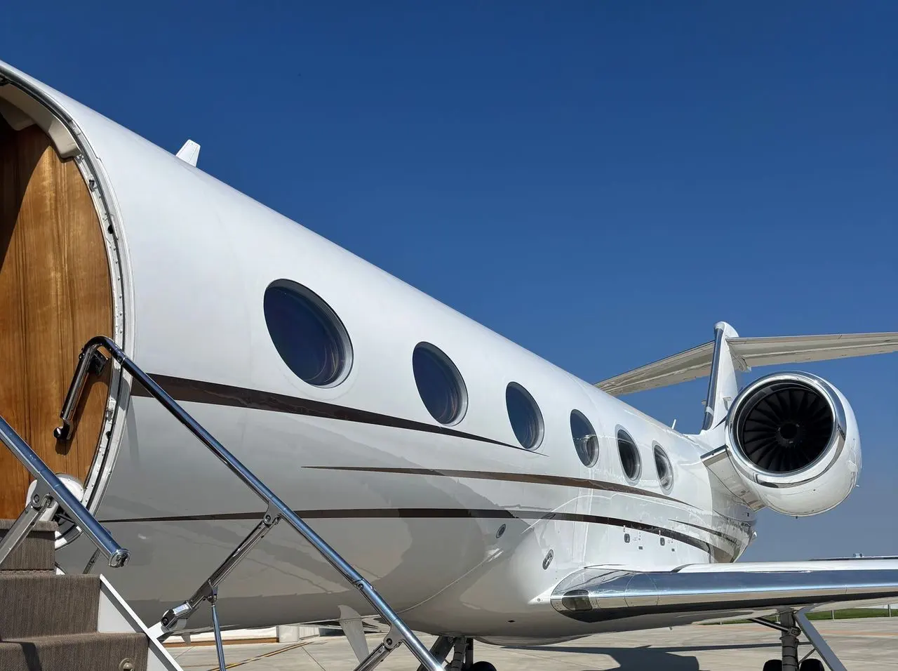 Close view of a large-cabin private jet with its wood-lined door open and the airstair down
