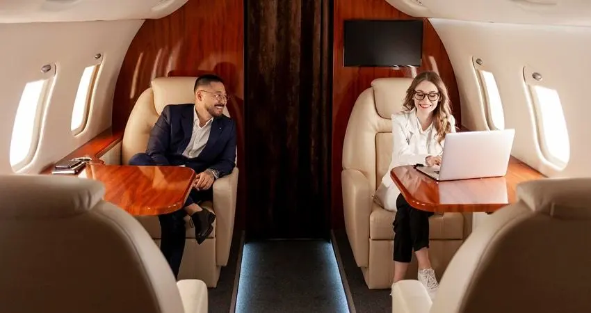 A man and a woman working with a laptop in a private jet cabin