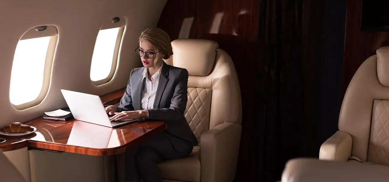 A businesswoman working on a laptop in a private jet cabin