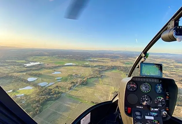 View from a helicopter cockpit over green countryside