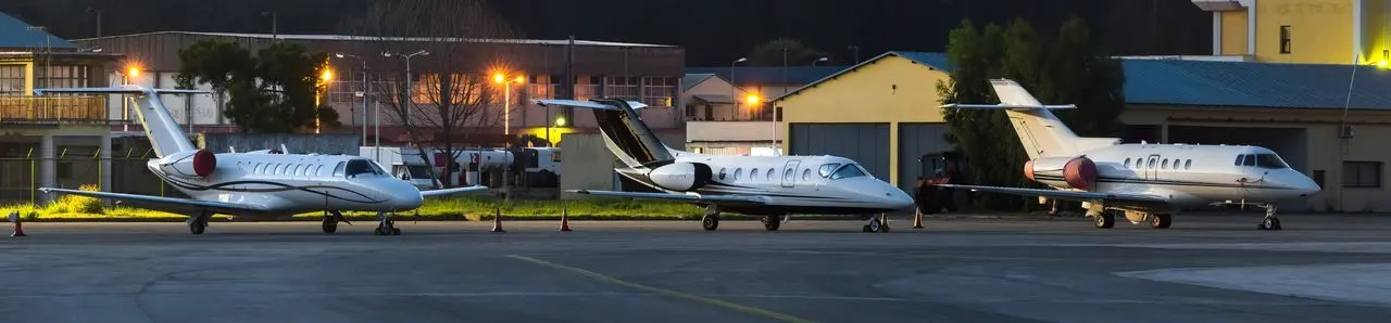 Private jets parked outside a business aviation terminal at dusk