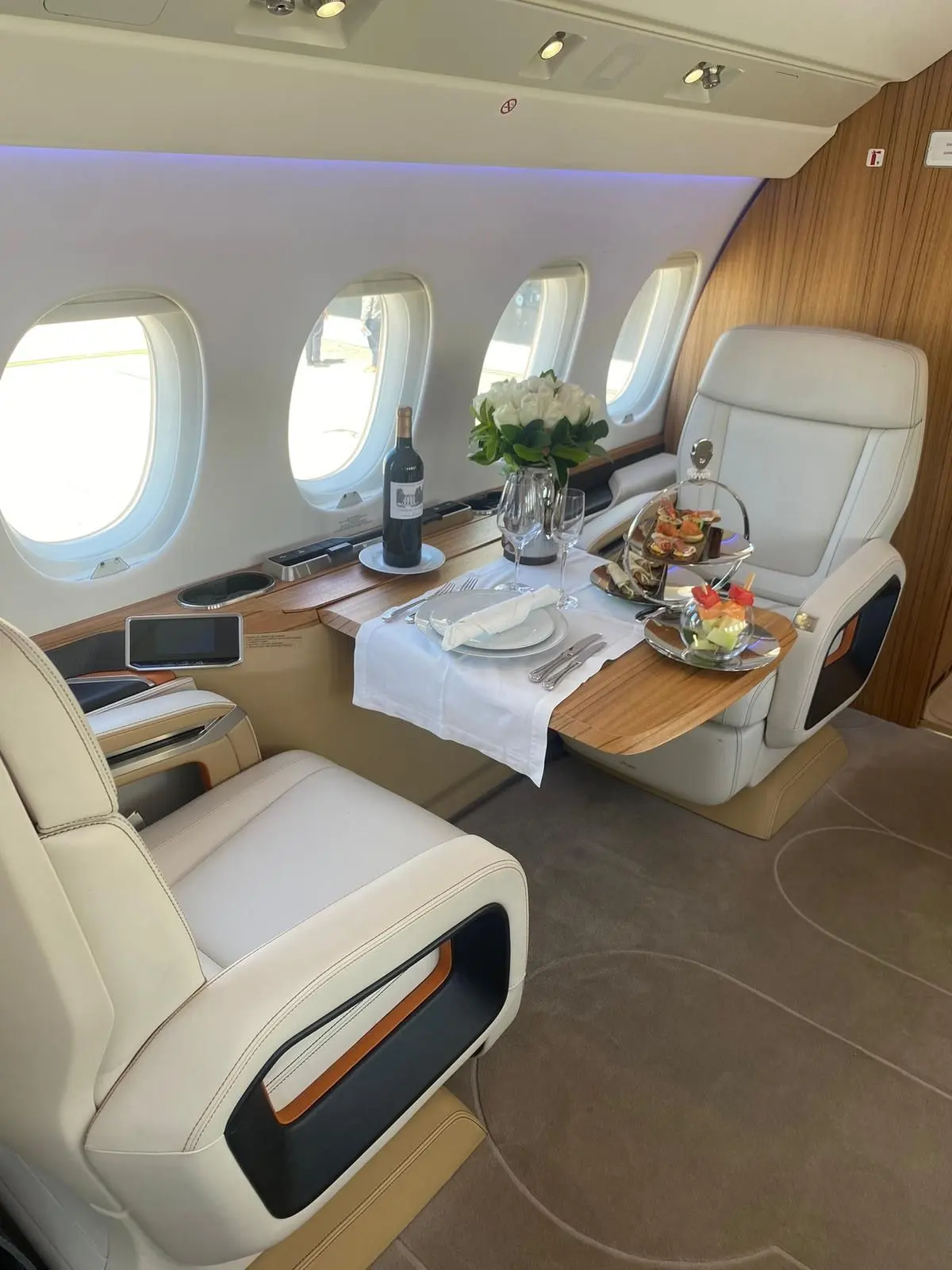 Private jet cabin with cream leather seating and a table set for dining