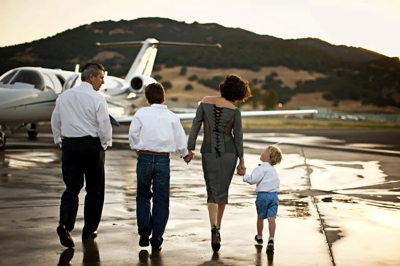 A family walking across the apron towards a private jet