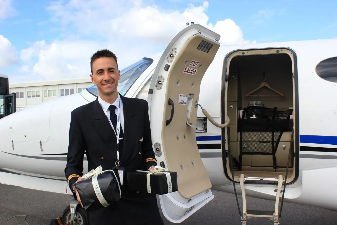 A pilot standing at the open door of a private jet