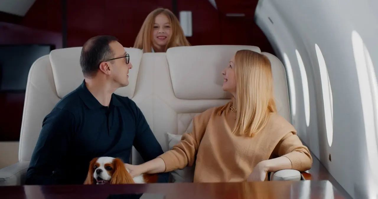 A family relaxing in a private jet cabin with their spaniel