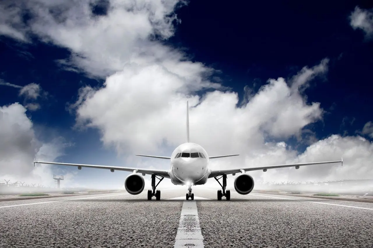 Aircraft on a runway beneath a bright sky and large clouds