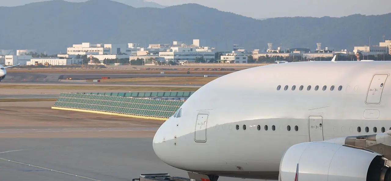 Large white VIP airliner on an airport apron with a city and mountains behind