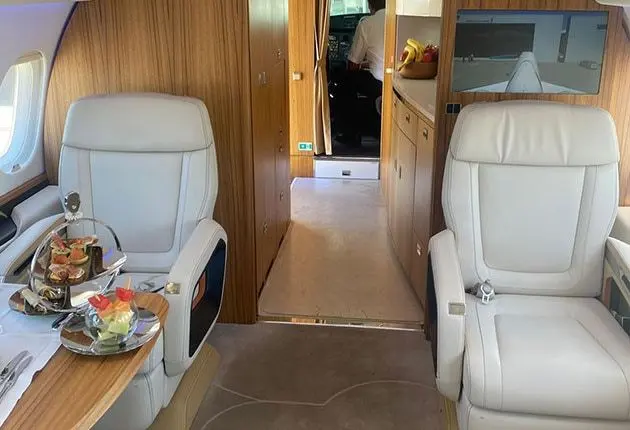 Private jet cabin interior with cream leather seats and a wood-panelled bulkhead