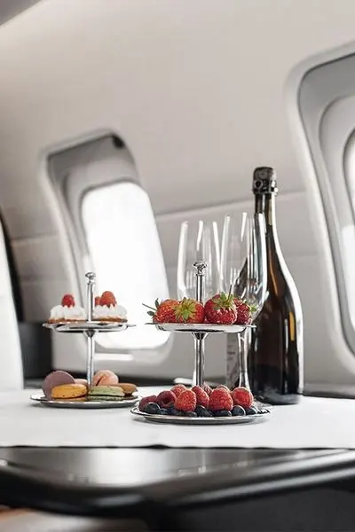 Champagne and a tiered platter of fruit and desserts served on a private jet table