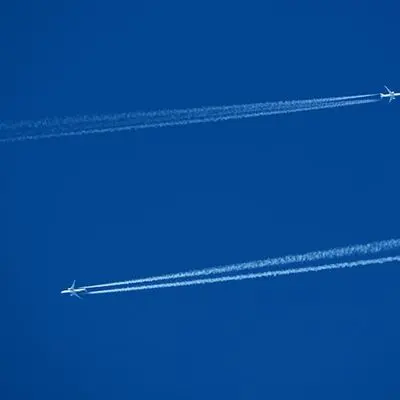 A jet at high altitude leaving contrails against a deep blue sky