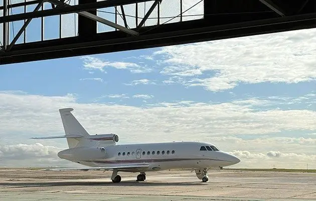 Private jet parked on the tarmac inside an open hangar