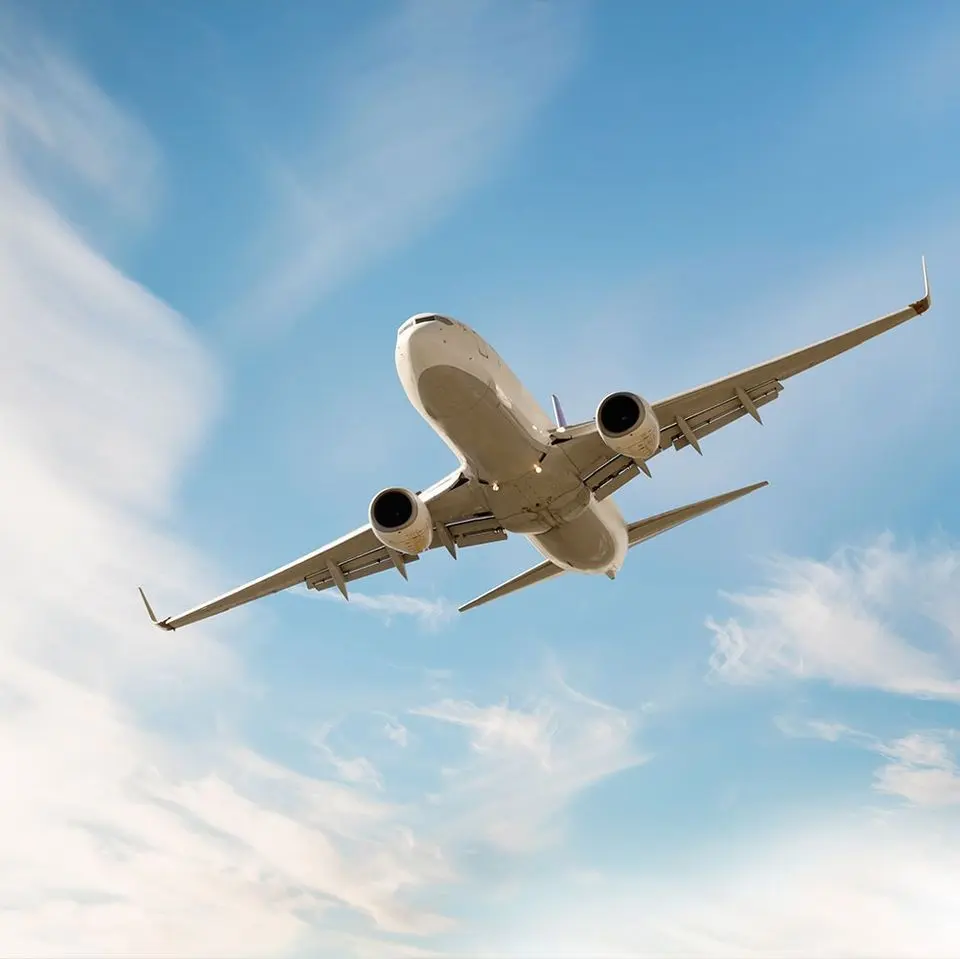 Private jet climbing against a blue sky with light clouds
