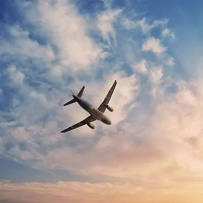 A private jet flying through a cloudy sky at sunset