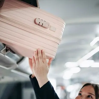 A passenger placing a suitcase into an overhead locker on board