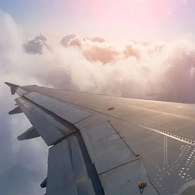Aircraft wing above the clouds during flight at sunrise